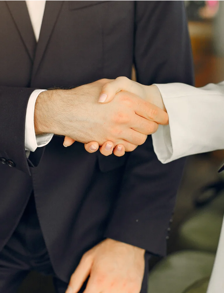 Detalle de manos estrechándose durante un encuentro profesional, representando los valores de confianza y relaciones reales en Somos Negocio.